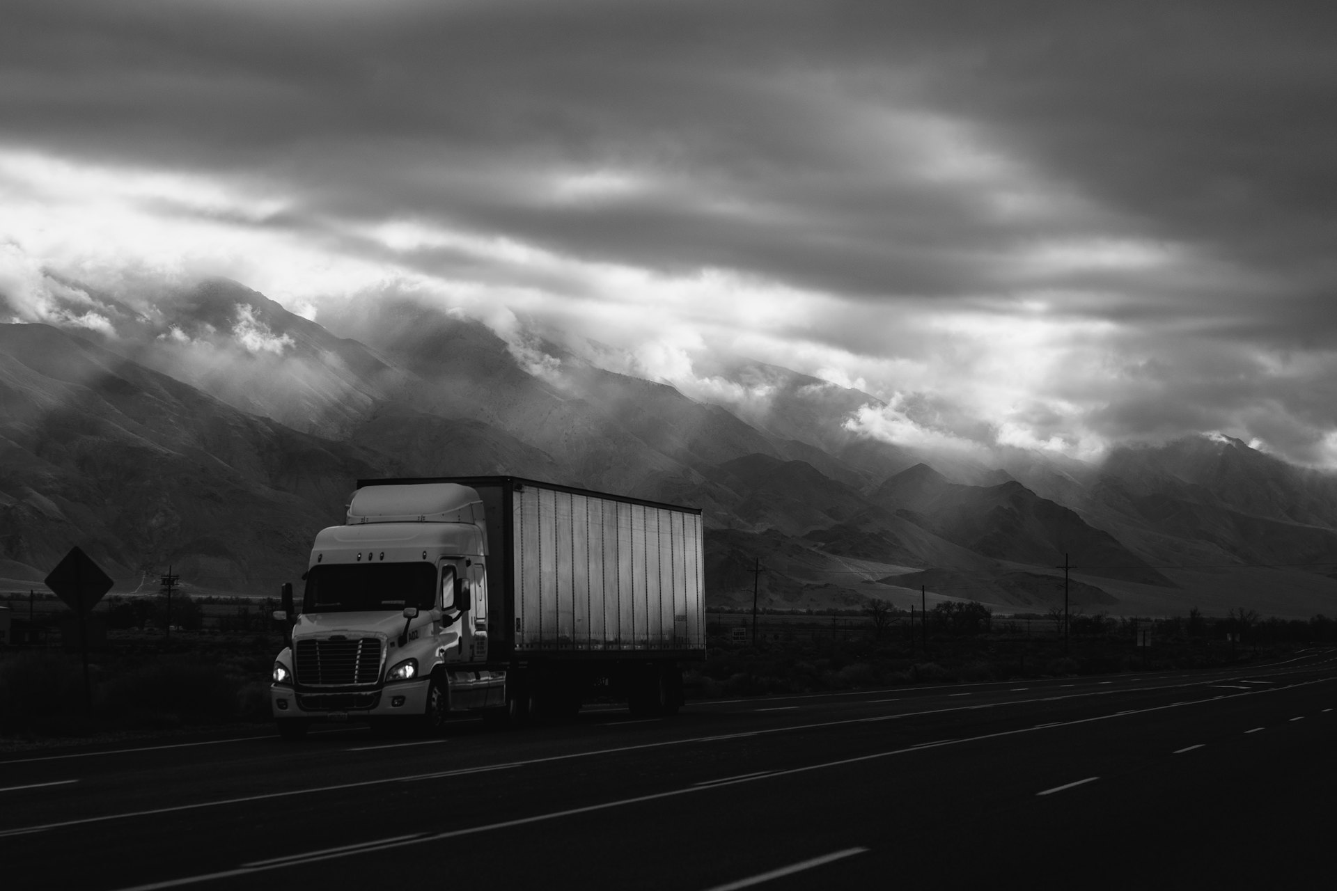 Semi truck driving into dramatic mountain light